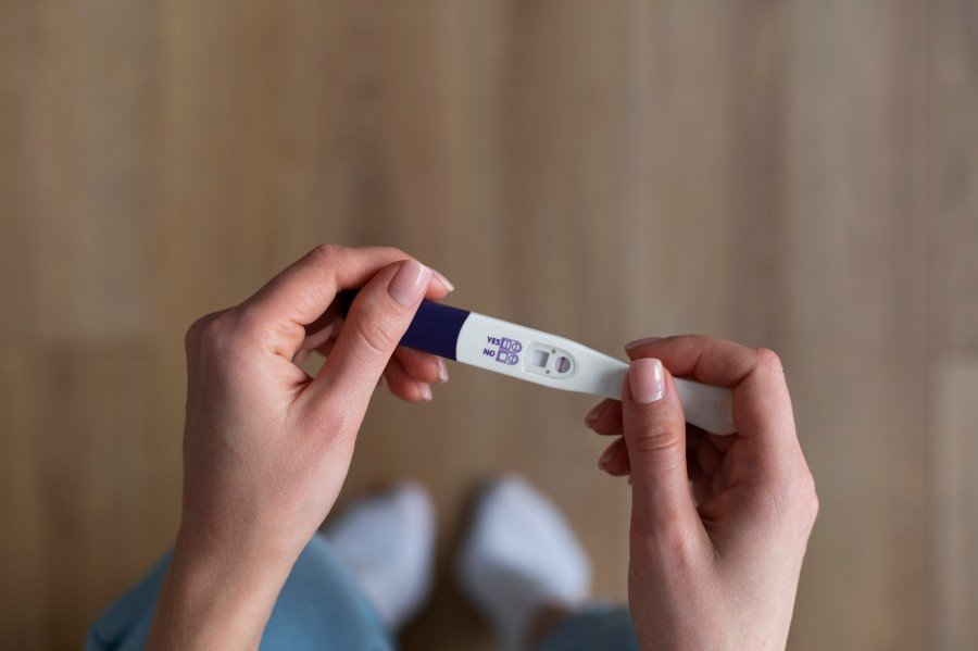 Woman holding a positive pregnancy test while checking the result