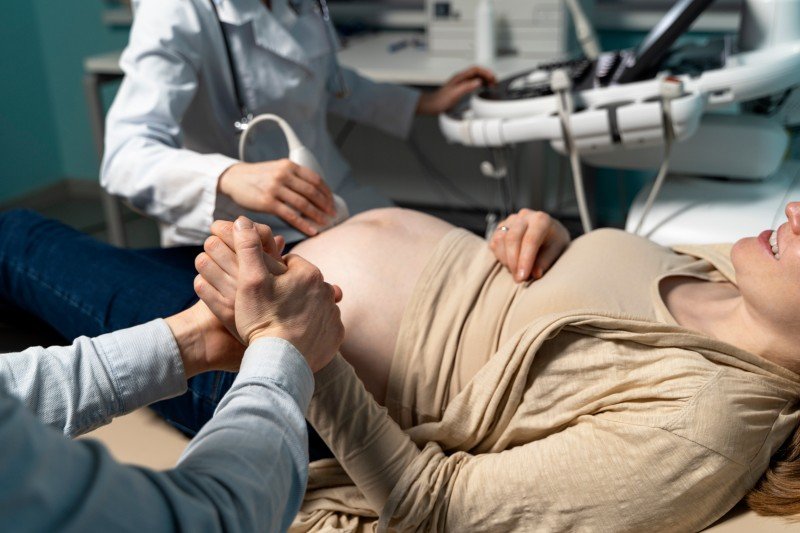 Pregnancy care consultation with a pregnant woman undergoing an ultrasound examination